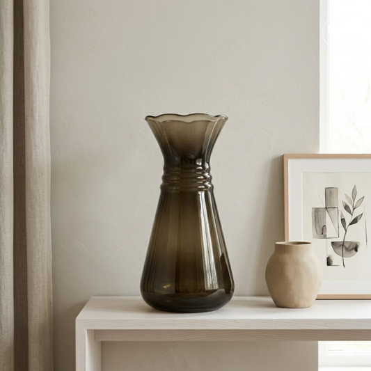 Mise en situation contemporaine et minimaliste du vase Art Déco en verre hyalite fumé marron posé sur une enfilade en bois clair, à côté d'un petit vase en céramique beige et d'un cadre, Galerie Popincourt | Contemporary minimalist lifestyle setting of the Art Deco smoked brown hyalite glass vase on a light wood console table, next to a small beige ceramic vase and a framed artwork, Galerie Popincourt