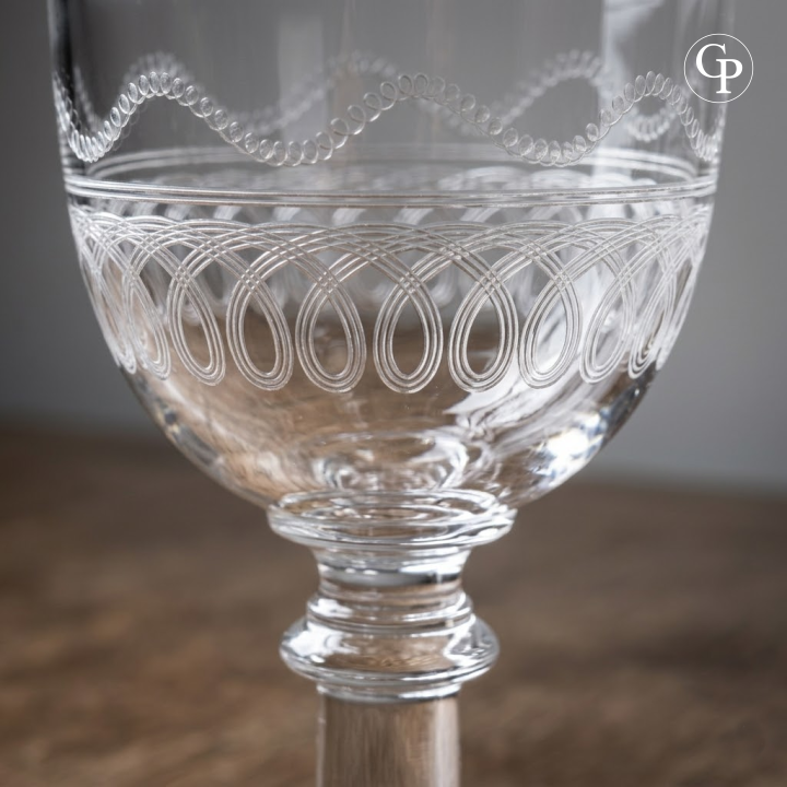 Macro de la frise d'entrelacs gravée et de la jambe à bouton d'un verre en cristal Val Saint Lambert modèle Lothaire | Macro shot of hand-engraved loop motif and stemmed leg on a Val Saint Lambert Lothaire crystal wine glass