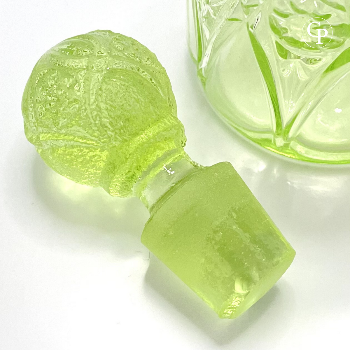 Close-up of the original faceted "pineapple" stopper in glowing Ouraline uranium glass, showing the hand-ground joint (émeri) for perfect fit on the Valambert n°12 Art Deco perfume bottle, circa 1935. | Gros plan sur le bouchon d'origine en forme de pomme de pin facettée en verre à l'uranium Ouraline luminescent, avec joint rodé (émeri) pour un ajustement parfait, flacon Valambert n°12 Art Déco, vers 1935.