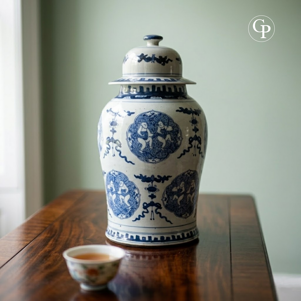 Mise en situation du grand vase balustre en porcelaine chinoise bleu et blanc sur une table en bois sombre avec une tasse à thé | Lifestyle view of the large Chinese blue and white porcelain baluster vase displayed on a dark wood table next to a teacup