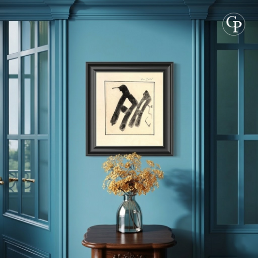 Framed minimalist black ink abstract calligraphy artwork by Hanna Ben-Dov on a blue living room wall with a wooden side table and dried flowers. | Encre abstraite minimaliste noire de Hanna Ben-Dov encadrée, sur un mur bleu de salon avec une table d'appoint en bois et des fleurs séchées.